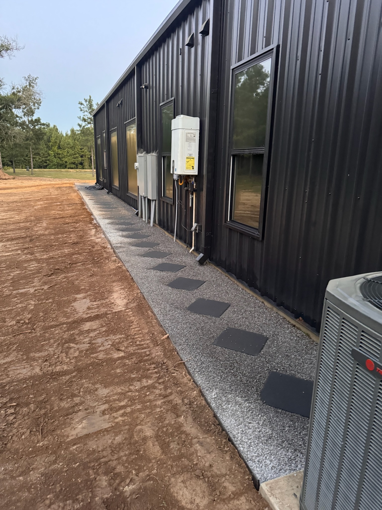 Freshly graded dirt and a finished gravel path along a shop building