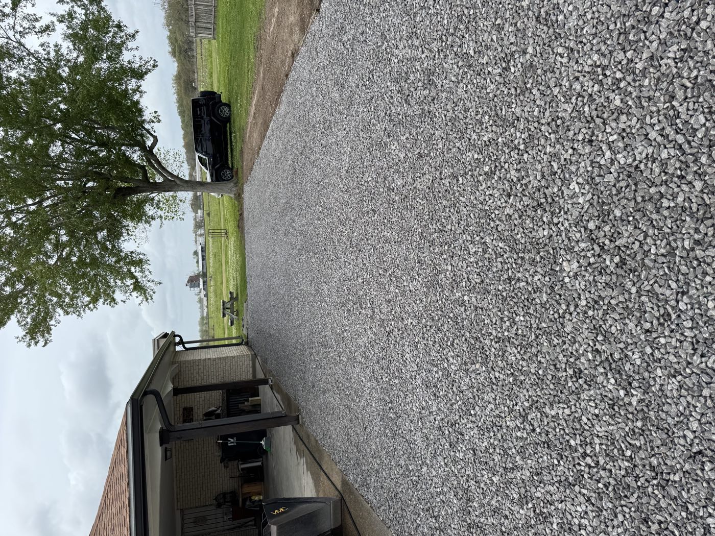 Freshly placed and compacted gravel driveway beside a house