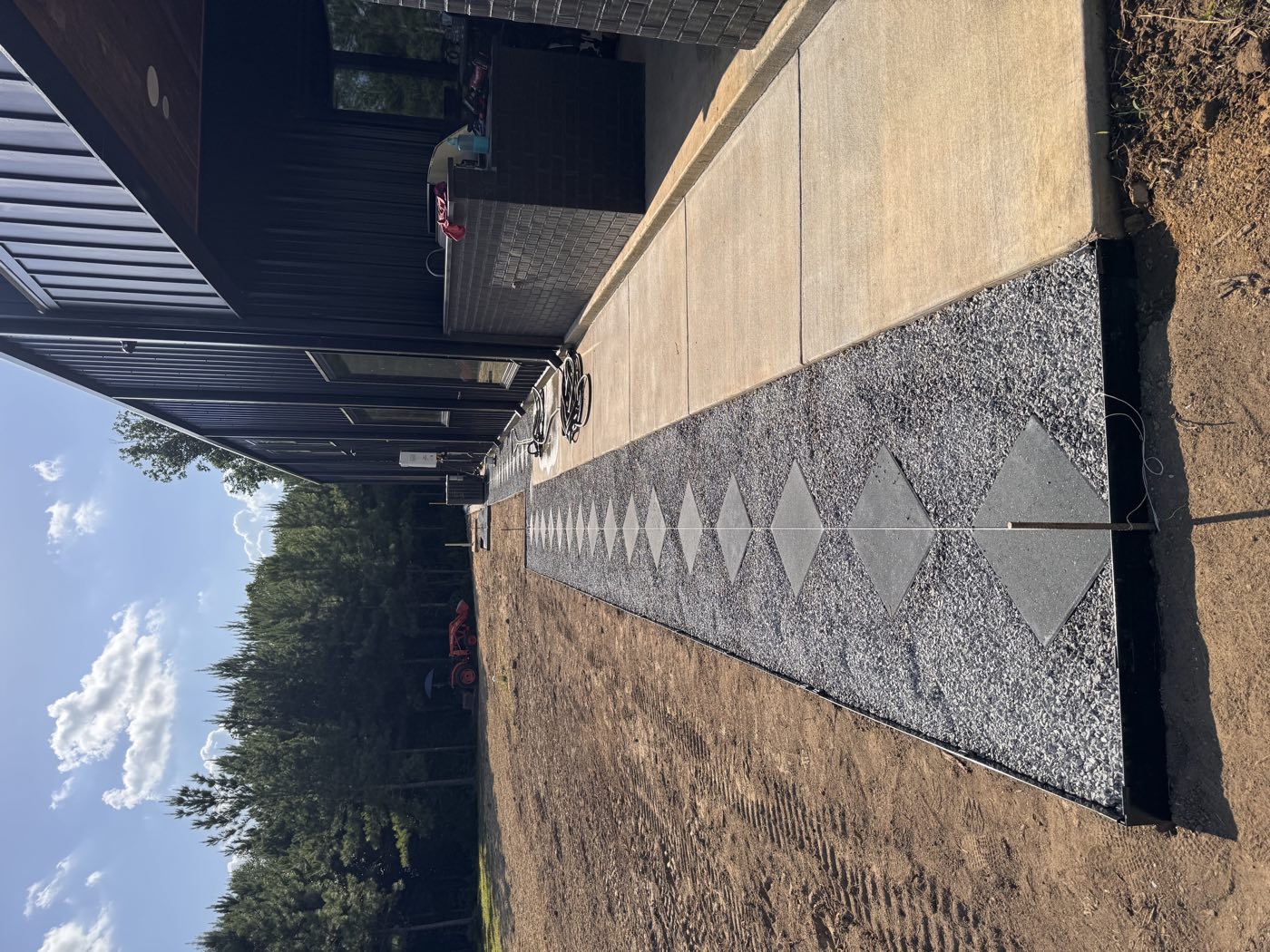 Diamond pavers set in a black gravel bed along a metal building patio