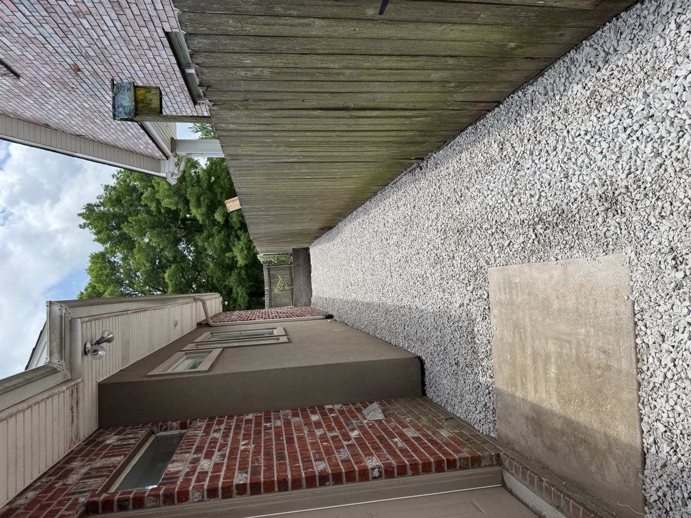 Finished white gravel side yard between a brick house and wood fence
