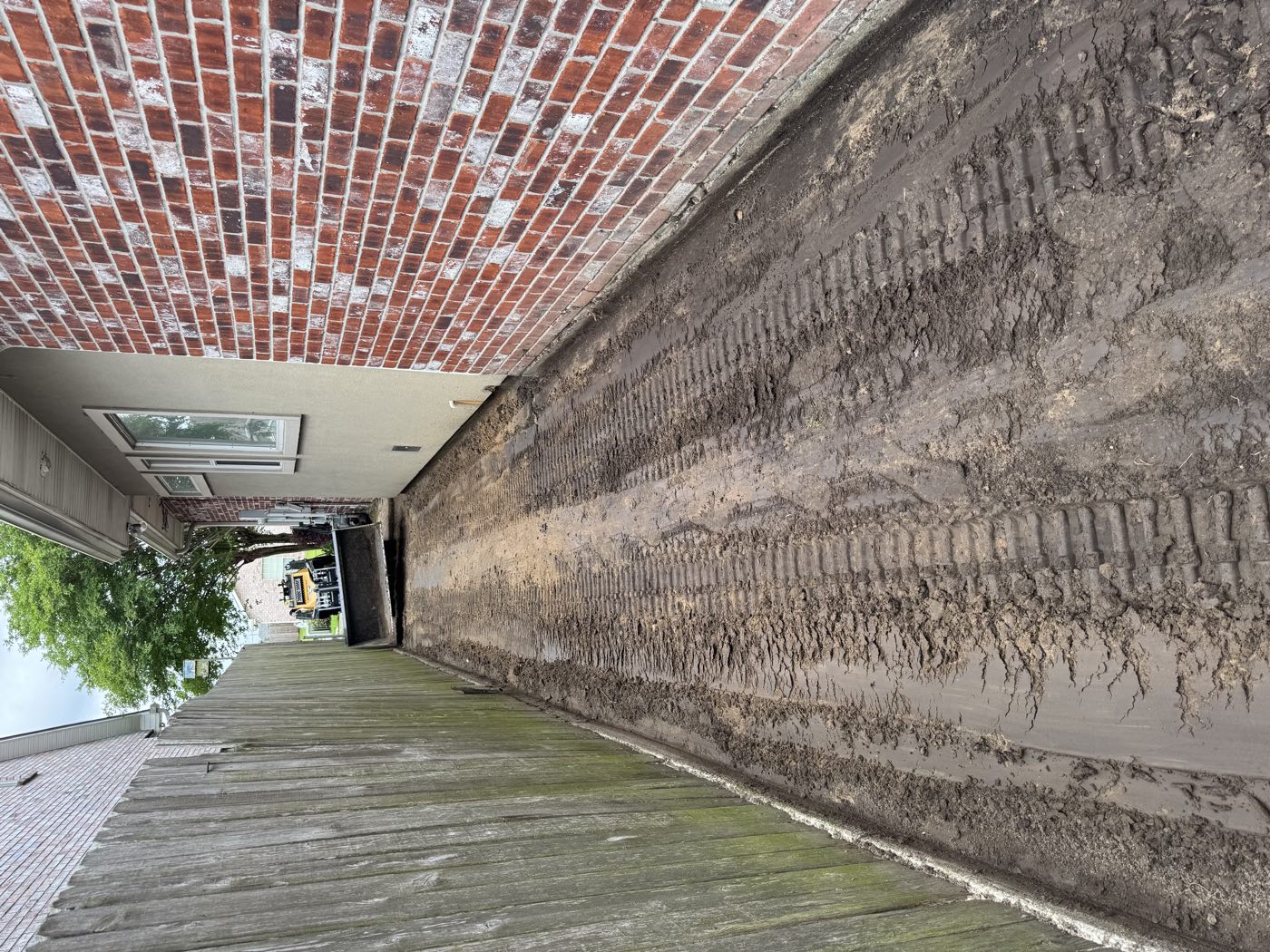 Narrow side yard stripped to dirt with track marks before gravel install