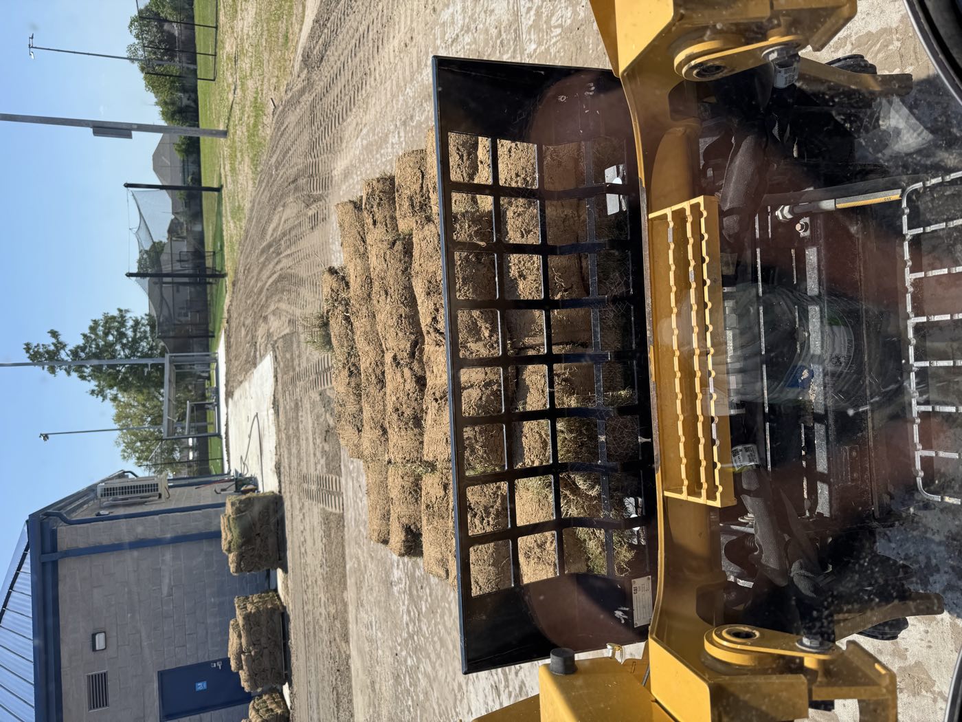 Pallets of sod on a loader fork at an athletic field